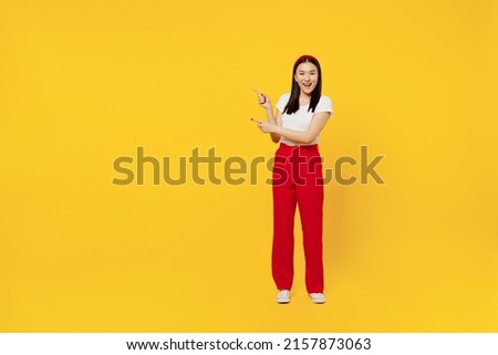 Full size body length promoter young woman of Asian ethnicity 20s years old in casual clothes point aside on workspace area copy space mock up isolated on plain yellow background studio portrait Royalty-Free Stock Photo #2157873063