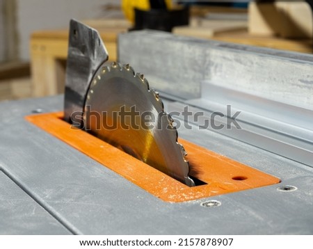 Close up of table saw circular blade riving knife anti kickback safety feature and deck inlay  selective focus on edge of blade and teeth Royalty-Free Stock Photo #2157878907