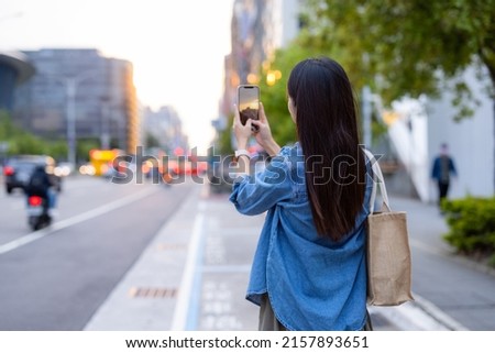 Woman use mobile phone to take photo in the street