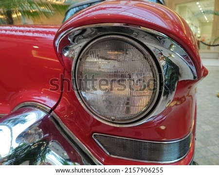 front part of a red classic car of the 60s with a round headlights. Fancy vintage retro car attracting the attention of visitors and amateurs of antiquity