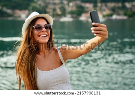 Beautiful woman having a good time at the beach on summer vacation, taking a selfie