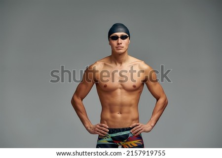 Portrait of a swimmer in a cap and mask, half-length portrait, young athlete swimmer wearing a cap and mask for swimming, copies of space, gray background. Royalty-Free Stock Photo #2157919755
