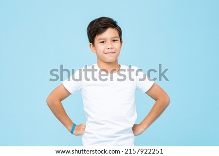 Cute mixed race boy smiling with arms akimbo in studio isolated light blue color background Royalty-Free Stock Photo #2157922251