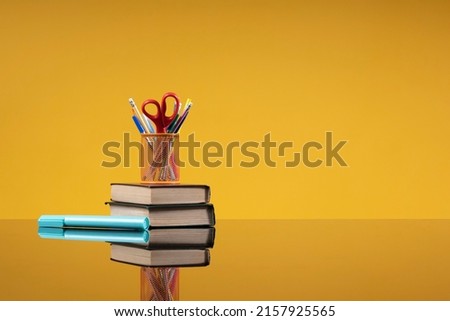 School accessories as a back to school concept. Writing materials on a stack of old books and a blue marker as a background with free space for the website of the school, institute, university