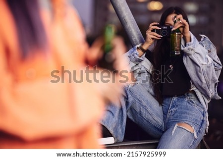 A teenager hanging on rooftop,taking photos and drinking beer.