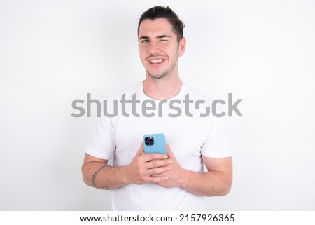 Young caucasian man wearing white t-shirt over white background taking a selfie  celebrating success