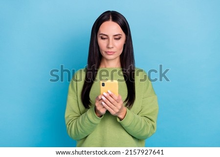 Portrait of calm serious girl hols use telephone typing comment isolated on blue color background