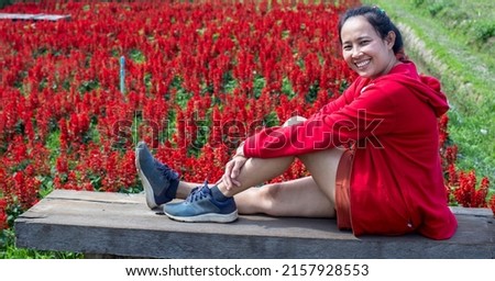 Asian woman sitting in a red flower field