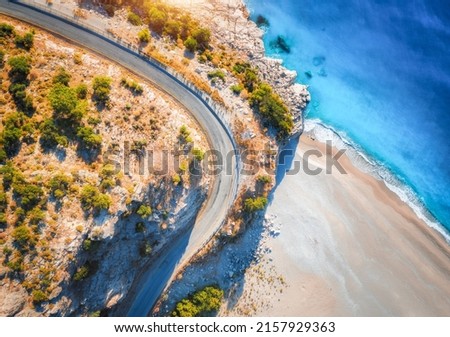 Aerial view of mountain road near blue sea with sandy beach at sunset in summer. Oludeniz, Turkey. Top view of road, trees, azure water, mountain. Beautiful landscape with highway, rocks, sea coast	 Royalty-Free Stock Photo #2157929363