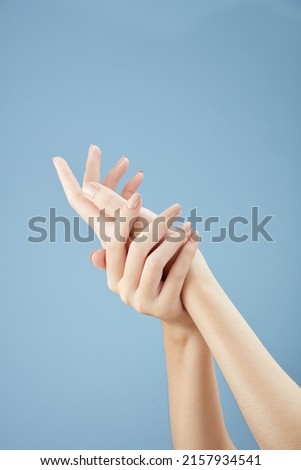 A front view of hand posing in blue background for cosmetic advertising