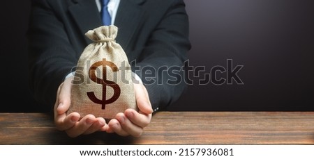 Businessman holds out dollar money bag. Getting a grant. Mortgage, loan approval. Easy Money. Salary, benefits, profit. Attracting investments. Deposit savings. Cashback. Banking and crediting. Royalty-Free Stock Photo #2157936081
