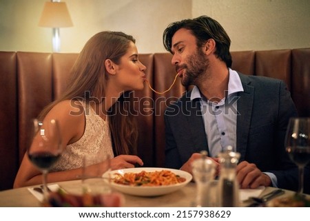 Nothing inspires romance quite like Italian food. Shot of a young couple sharing spaghetti during a romantic dinner at a restaurant. Royalty-Free Stock Photo #2157938629