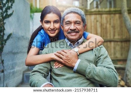 She has helped me some difficult times. Portrait of a cheerful young female nurse holding a elderly patient in a wheelchair as support outside during the day. Royalty-Free Stock Photo #2157938711