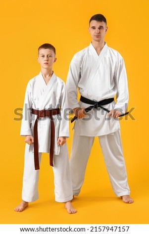 Boy and instructor in karategi on yellow background Royalty-Free Stock Photo #2157947157