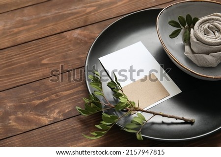 Table setting with blank card and tree branch on wooden background