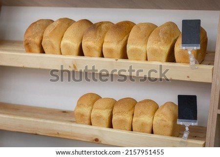 Bricks of wheat bread lie on wooden shelves in store. Fresh delicious of bread loaves in bakery, baker shop. High quality photo