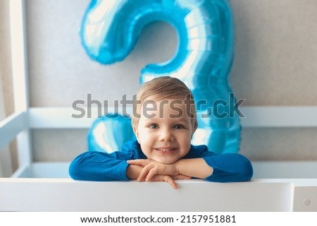 Portrait of happy smiling little boy celebrating birthday for three years old with big blue balloon with number 3 Royalty-Free Stock Photo #2157951881