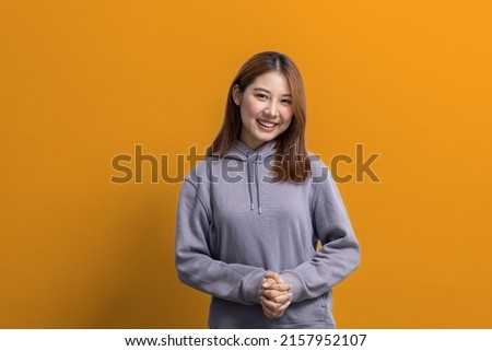 Portrait of beautiful Asian woman doing cheerful pose on isolated yellow background, portrait concept used for advertisement and signage, isolated over yellow background, copy space.