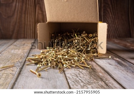 Screws, box of screws photographed on rustic wood, selective focus.