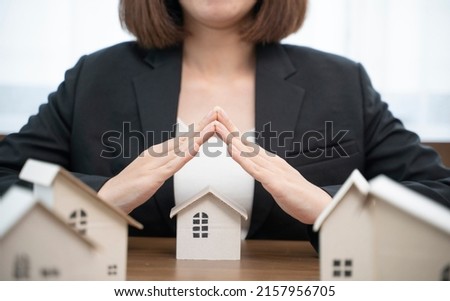 House covered by real estate insurance broker agent woman hands protecting gesture of man and symbol of house. Property insurance and security concept. 