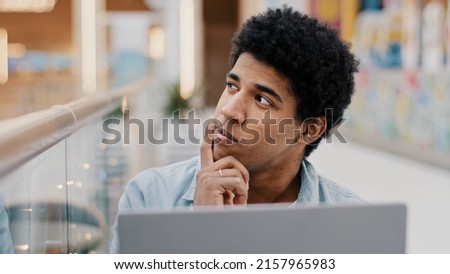 Pensive male african american guy rubbing chin thinking solution problem plan strategy startup idea sitting with laptop indoor male writer composing novel journalist working deep in thought difficulty Royalty-Free Stock Photo #2157965983