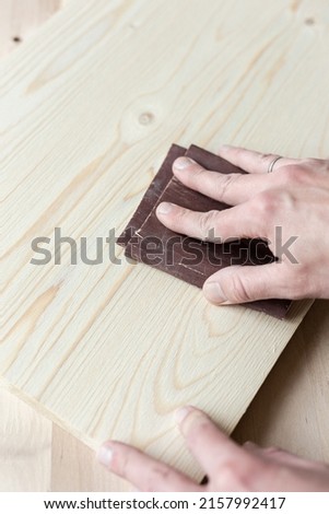 Sanding boards by hand. Sanding with abrasive paper. Royalty-Free Stock Photo #2157992417
