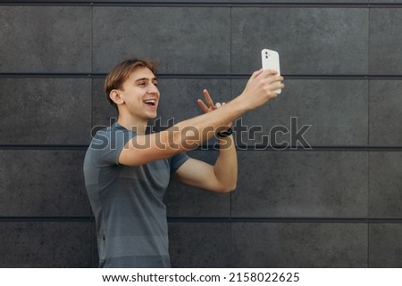 sporty guy making selfie photo on black wall