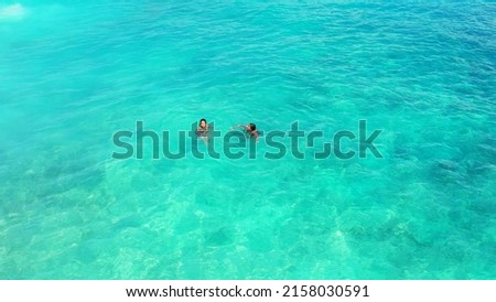 A aerial Shot girls swim in the turquoise, clear water of Gili Meno Island, Lombok, Indonesia 