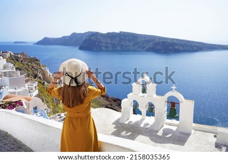 Tourism in Europe. Back view of young woman looking stunning landscape in the picturesque village of Oia, Santorini Island, Greece. Royalty-Free Stock Photo #2158035365