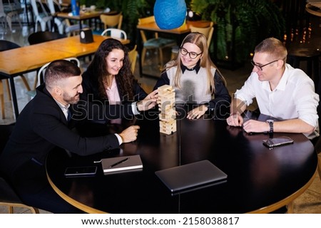 Businessmen are playing Jenga games. They sit in the office and play games. Concept photo for design and work.