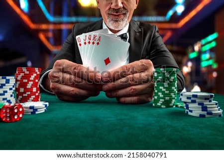 Gambling concept. Close up of Poker Player male hand Winning Royal Flush at casino, gambling club. Сasino chips or Casino tokens,  dice, poker cards, gambling man lucky guy, games of chance. Royalty-Free Stock Photo #2158040791