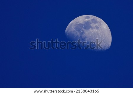 A scenic view of a half-moon illuminating the blue sky