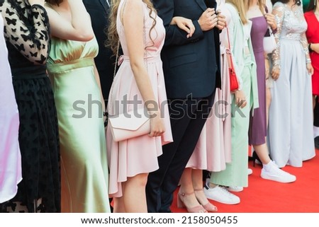 Prom guests standing on a red carpet, close up photo