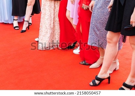 Feet of prom guests, girls stand on a red carpet, close up photo
