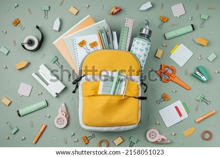 Opened School backpack with stationery  on green background. Concept back to school. School supplies. Royalty-Free Stock Photo #2158051023