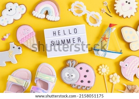 Hello summer text on lightbox and cute summer symbols on yellow background. Top view, Flat lay. Creative summer concept..