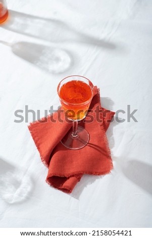 Summer concept with hard sun light, red cocktail on the white tableclolth, selective focus image
