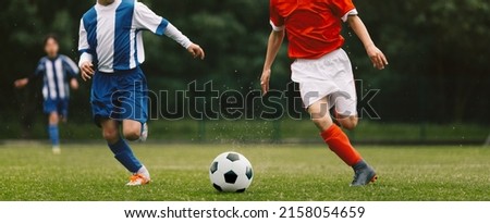 Young Boys Compete in Tournament Match in a Duel. Football Game on Summer Sunny Day. School Kids in Blue and Red Jersey Uniforms Running Classic Soccer Ball on Grass Pitch Royalty-Free Stock Photo #2158054659