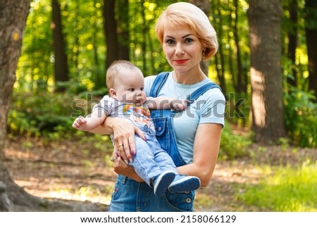 beautiful girl holding a child in her arms in a summer park close-up