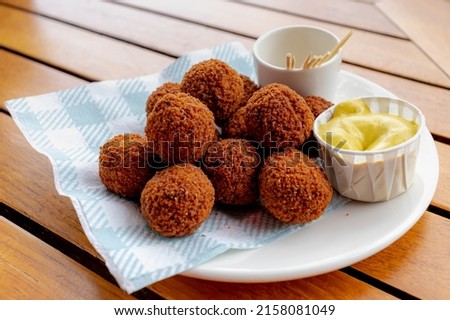 Bitterballen, Dutch meat-based snack in white plate served with mustard on wooden tabel background, Typically containing a mixture of beef or veal, Bitterballen are one of Holland's favorite snacks. Royalty-Free Stock Photo #2158081049