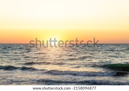 Scenic panoramic view of bright warm red orange dramatica sunrise or sunset at early morning over sand coast of ocean water surface. Beautiful seaside golden dusk panorama background on stormy sea