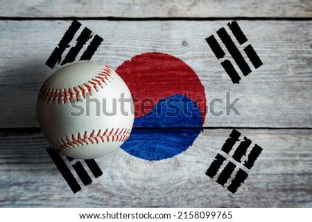Leather baseball on rustic wooden background painted with South Korean flag and copy space. South Korea is one of the top baseball nations in the world.