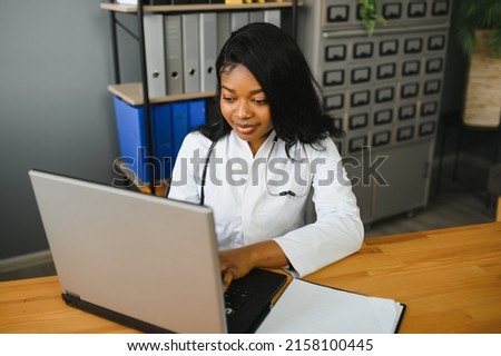 healthcare, medical and technology concept - african female doctor with laptop. Royalty-Free Stock Photo #2158100445