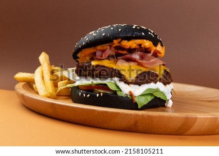 Classic burger with black bun. With bacon, cheese and salad. Selective focus.