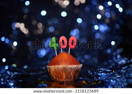 Tasty homemade vanilla anniversary cupcake with number 400 four hundred on aluminium foil and blurred bright background in minimalistic style. Digital gift card birthday concept. High quality image