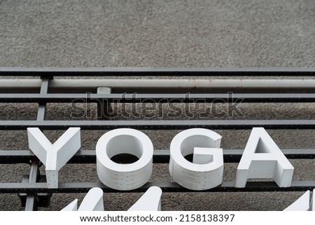 A sign of the word yoga hangs on the wall, white text letters, meditation, fitness room, voluminous printed letters. High quality photo