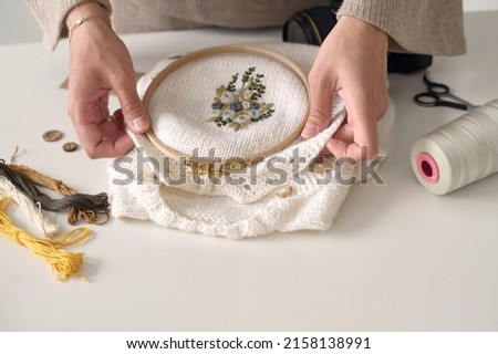 A young beautiful seamstress embroiders on clothes