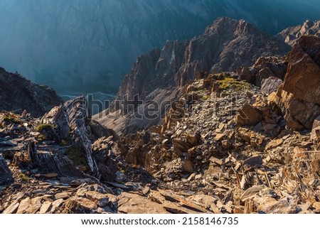 Awesome mountain view from cliff at very high altitude. Scenic landscape with beautiful sharp rocks near precipice and couloirs in sunlight. Beautiful mountain scenery on abyss edge with sharp stones. Royalty-Free Stock Photo #2158146735