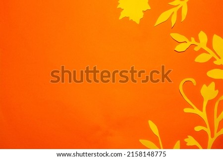 orange paper with yellow jungle flowers and leaves along the edge of the frame, creative tropical design, copy space, flat lay