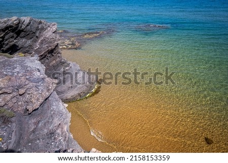 Beach with crystalline and transparent waters of bluish and greenish colors with golden sand and gray and purple rocks. Summer and vacation feeling. Cartagena, Region of Murcia, Spain Royalty-Free Stock Photo #2158153359